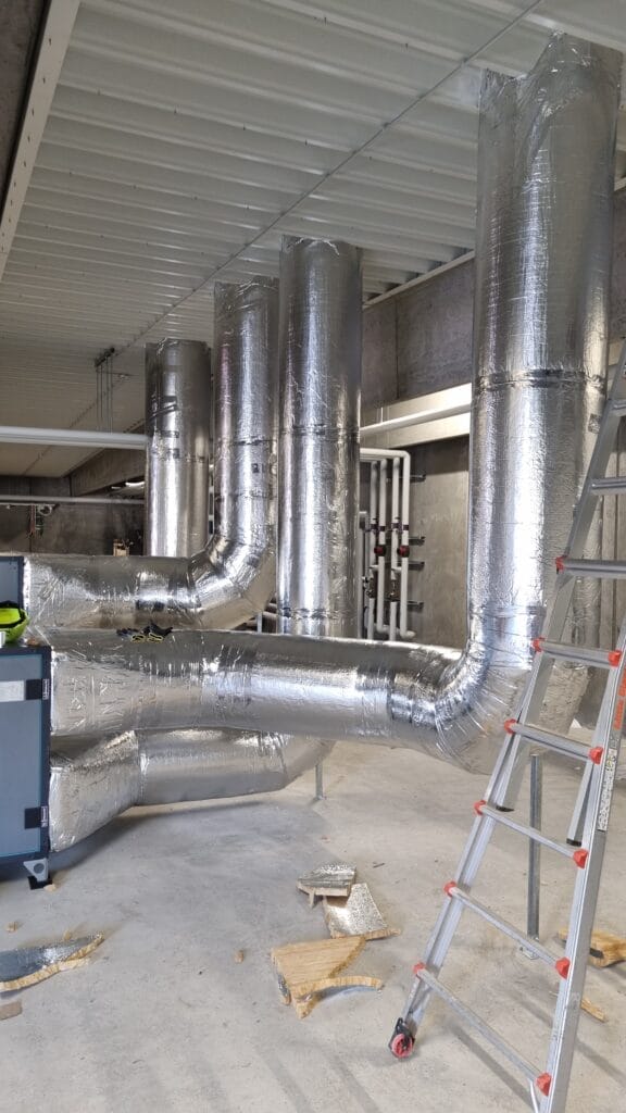 Store sølv-isolerede ventilationsrør i industrihal